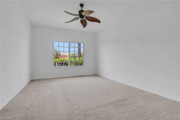 an empty room with windows and ceiling fan view