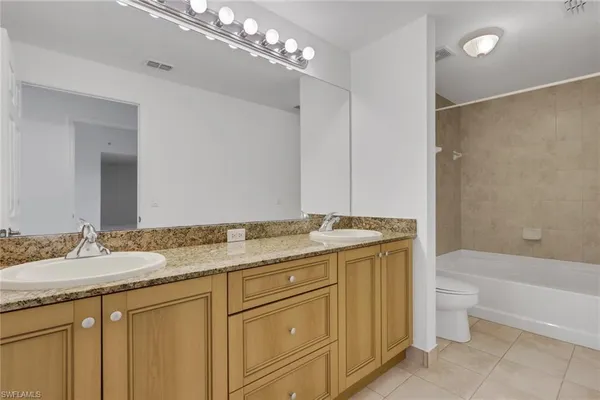 a bathroom with a granite countertop sink a toilet and shower