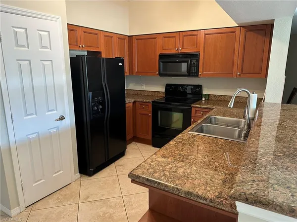 a kitchen with stainless steel appliances kitchen island granite countertop a refrigerator stove and sink