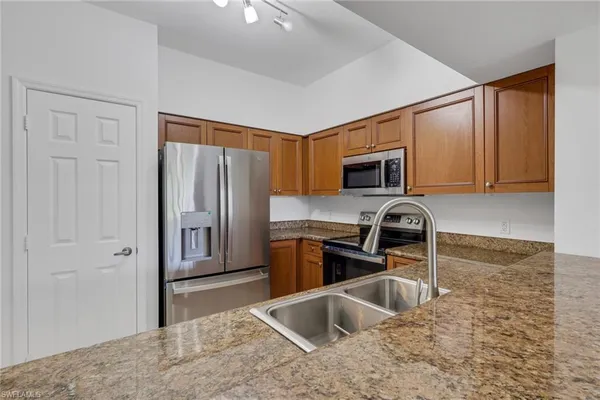 a kitchen with granite countertop a refrigerator stove and sink
