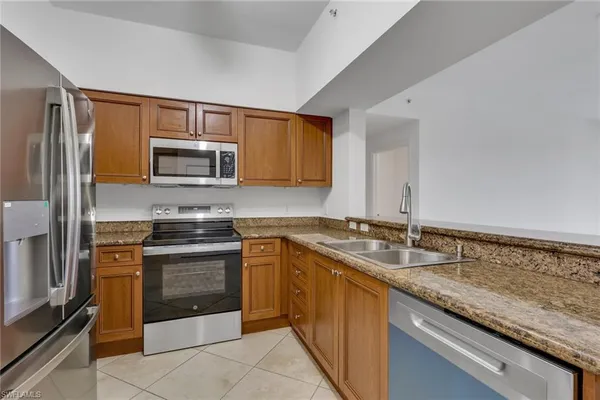 a kitchen with stainless steel appliances granite countertop a sink stove microwave and refrigerator