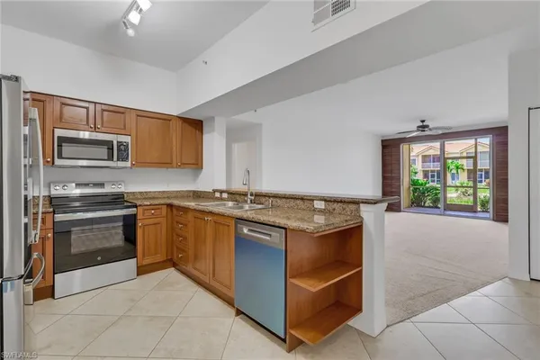 a kitchen with stainless steel appliances granite countertop a stove top oven a sink dishwasher a refrigerator and a microwave oven