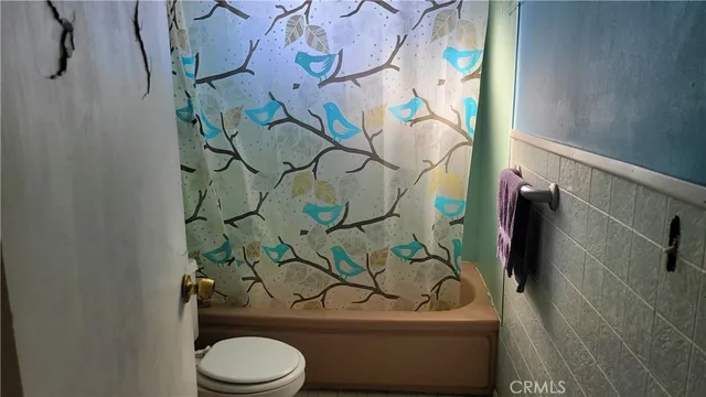 a bathroom with a toilet and shower curtain