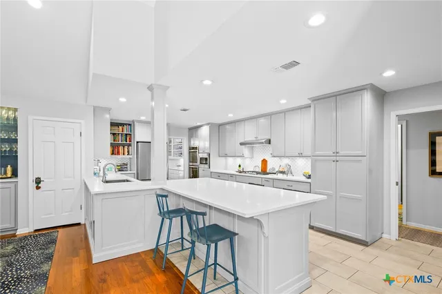 a kitchen with stainless steel appliances a refrigerator a sink dishwasher and a refrigerator with wooden floor