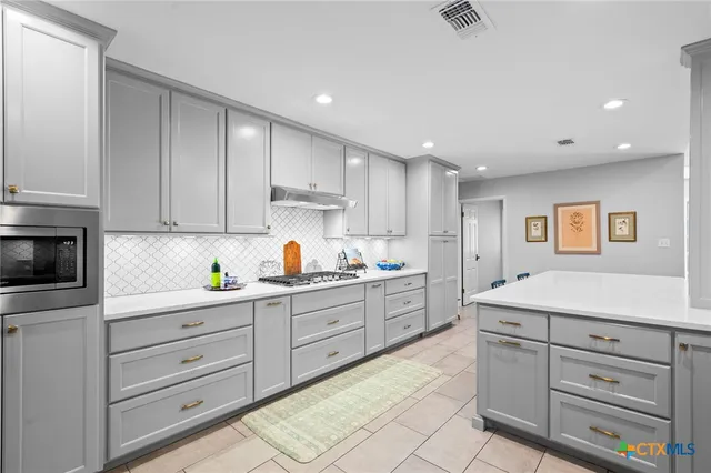a kitchen with white cabinets and appliances