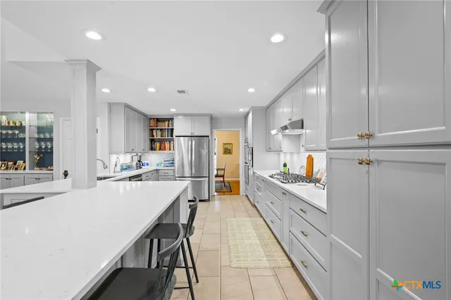 a large white kitchen with lots of counter space wooden floor and appliances