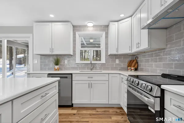 a kitchen with stainless steel appliances granite countertop a sink stove and cabinets