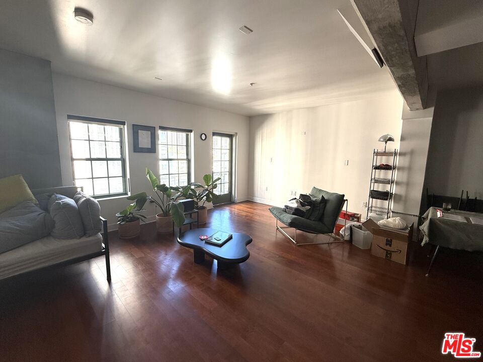 416 South Spring Street, Unit 905 Los Angeles, CA 90013 - Photo 4 of 19 a living room with couches a coffee table and a dining table with wooden floor