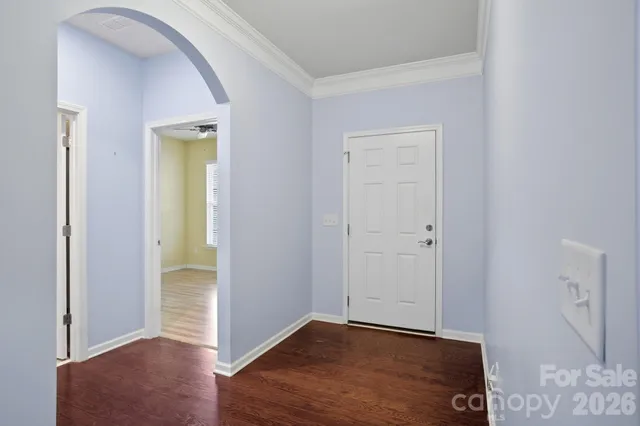a view of an empty room with wooden floor and a bathroom