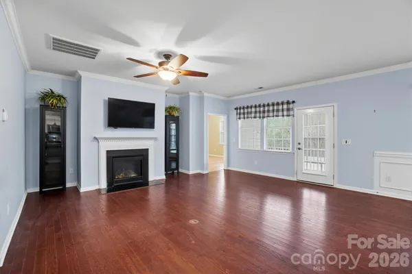 a view of an empty room with wooden floor fireplace and a window