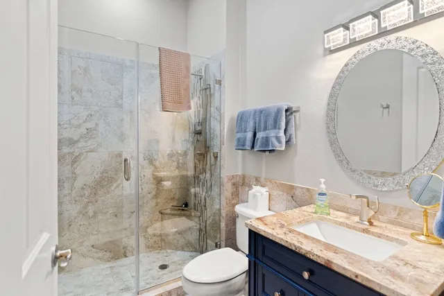 a bathroom with a granite countertop sink toilet a mirror and shower