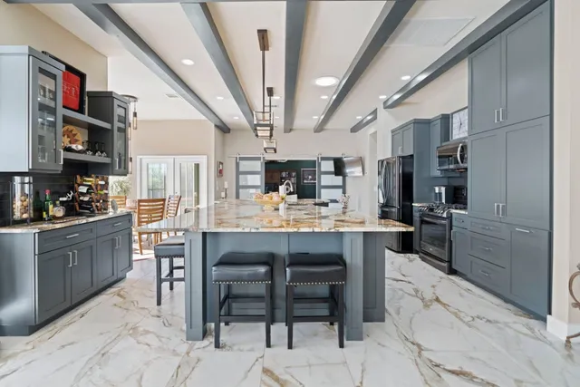 a kitchen with stainless steel appliances kitchen island granite countertop a table chairs sink and cabinets