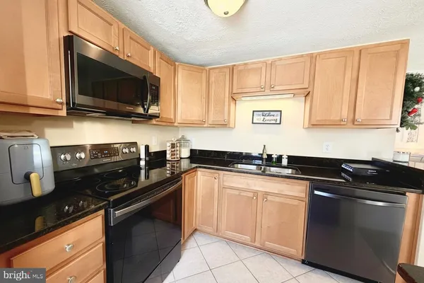 a kitchen with stainless steel appliances granite countertop a sink dishwasher stove and microwave with wooden cabinets