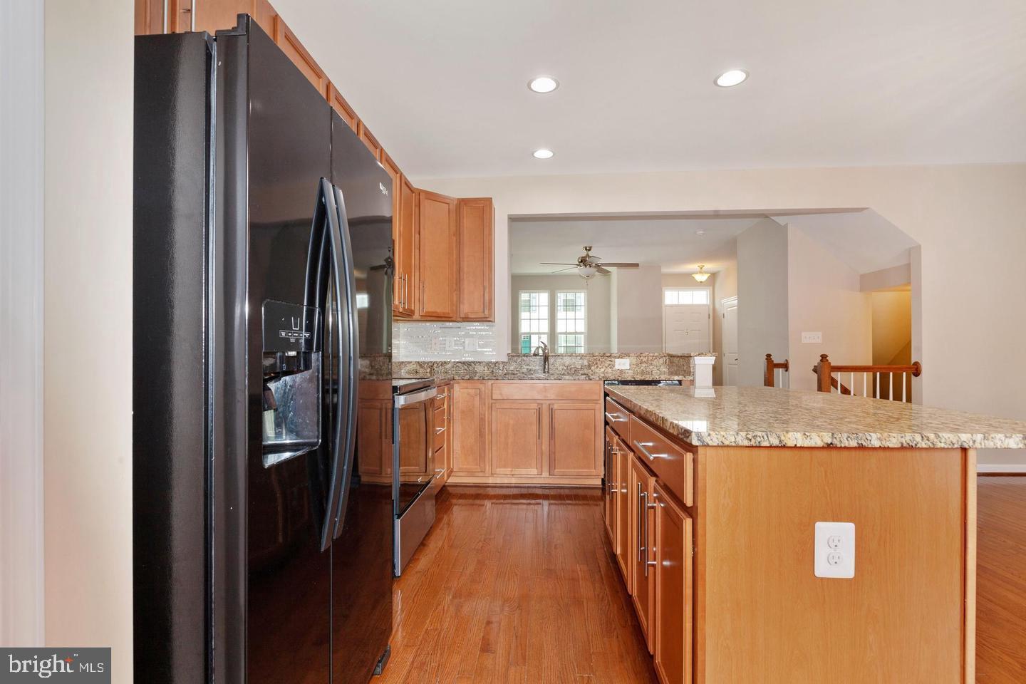 9418 Paragon Court Owings Mills, MD 21117 - Photo 15 of 42 a kitchen with kitchen island granite countertop a refrigerator a sink and wooden cabinets