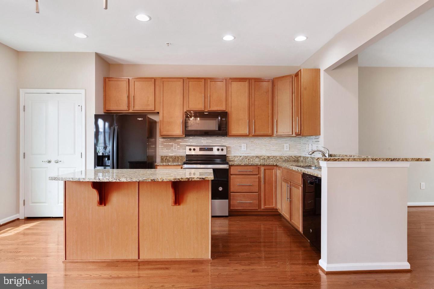 9418 Paragon Court Owings Mills, MD 21117 - Photo 16 of 42 a kitchen with stainless steel appliances granite countertop a stove top oven a sink dishwasher and a refrigerator with wooden floor