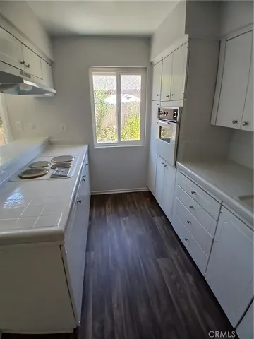 a kitchen with white cabinets and wooden floor