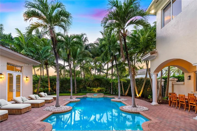 a view of a swimming pool with chairs and table in the patio