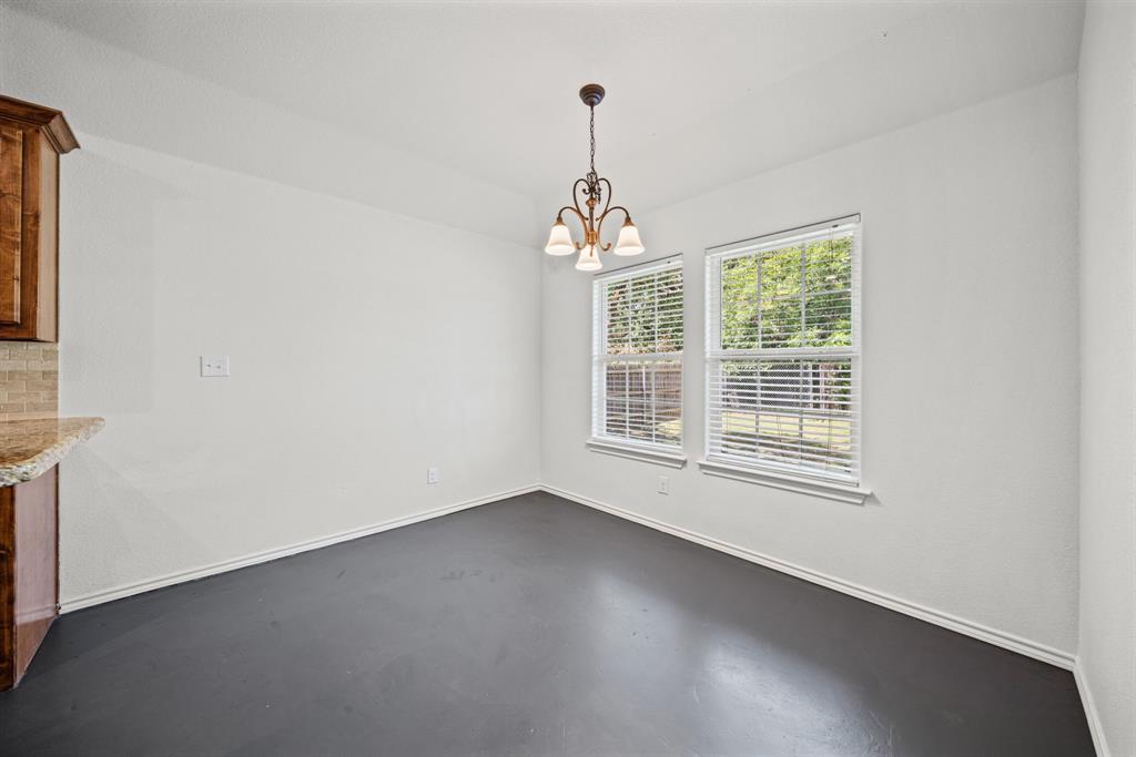 229 Firefly Drive Springtown, TX 76082 - Photo 9 of 33 Bright interior space featuring a dark flooring, white walls, and a decorative chandelier