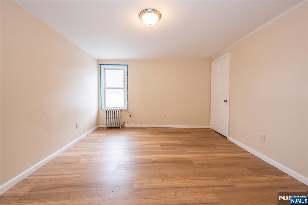 153 Augusta Street Irvington, NJ 07111 - Photo 22 of 26 an empty room with wooden floor and windows