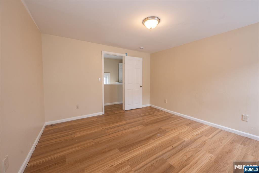 153 Augusta Street Irvington, NJ 07111 - Photo 23 of 26 a view of an empty room with wooden floor and a window