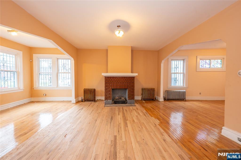 153 Augusta Street Irvington, NJ 07111 - Photo 4 of 26 wooden floor fireplace and windows in an empty room