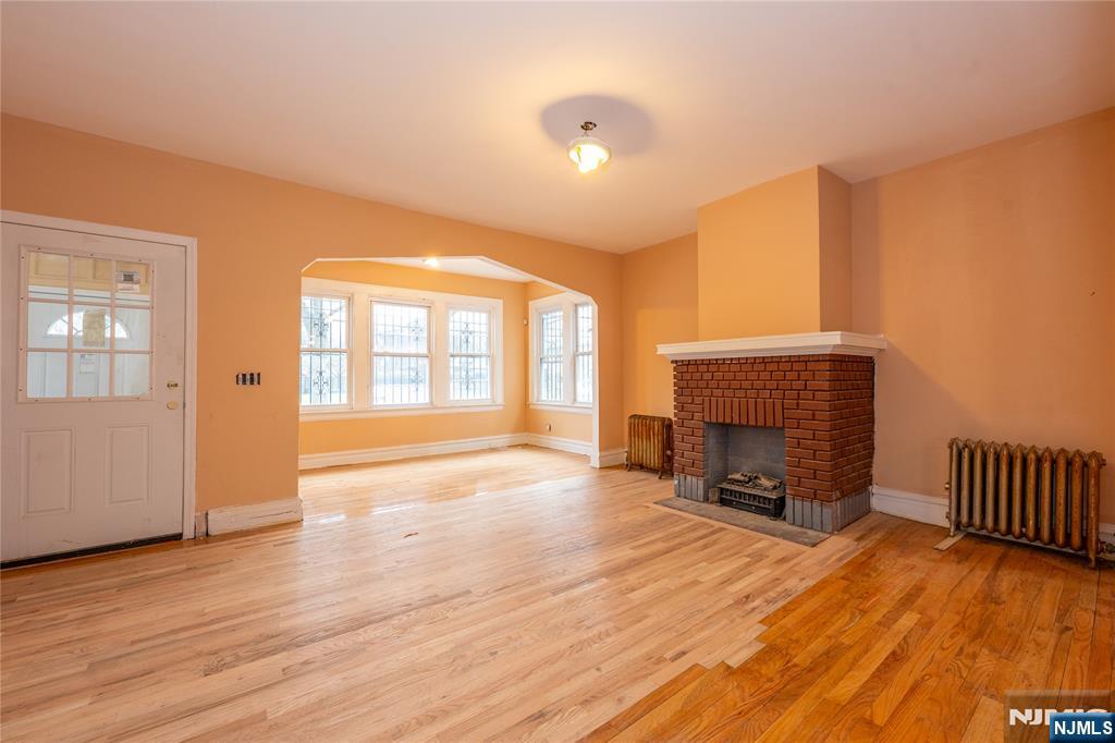 153 Augusta Street Irvington, NJ 07111 - Photo 6 of 26 a view of empty room with fireplace and wooden floor
