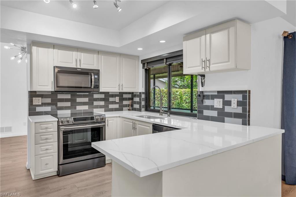102 Muirfield Circle Naples, FL 34113 - Photo 12 of 43 a kitchen with stainless steel appliances granite countertop a stove and a sink