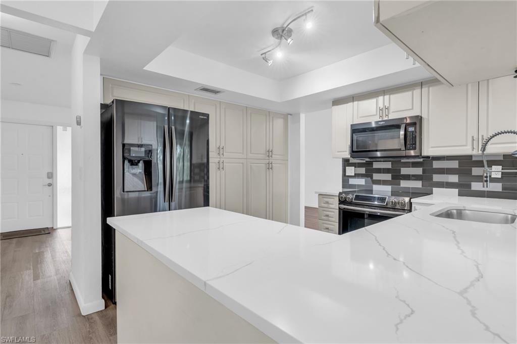102 Muirfield Circle Naples, FL 34113 - Photo 14 of 43 a kitchen with stainless steel appliances a refrigerator and a stove top oven