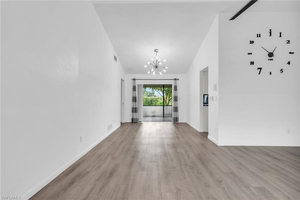 102 Muirfield Circle Naples, FL 34113 - Photo 9 of 43 wooden floor in an empty room with a window
