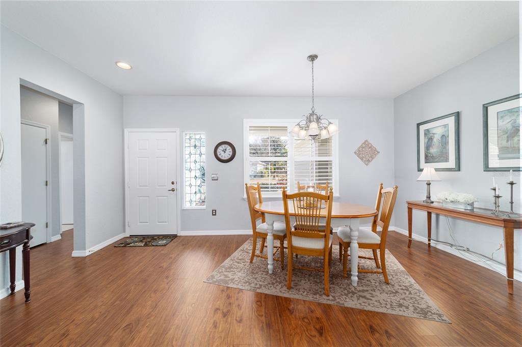 13146 Southeast 93rd Terrace Road Summerfield, FL 34491 - Photo 23 of 63 a dining room with wooden floor a chandelier a wooden table and chairs