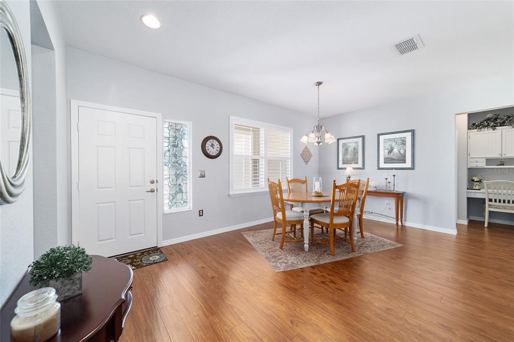 13146 Southeast 93rd Terrace Road Summerfield, FL 34491 - Photo 8 of 63 a dining room with wooden floor a chandelier a wooden table and chairs