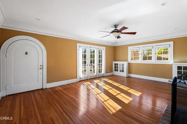 a view of empty room with wooden floor and fan