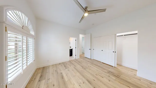 a view of empty room with wooden floor and fan