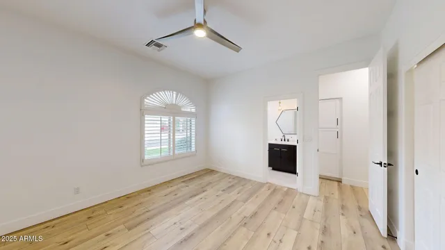 a view of empty room with wooden floor and fan