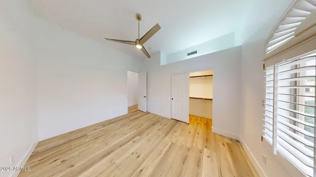 a view of empty room with wooden floor and fan