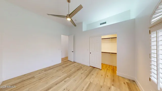 a view of empty room with wooden floor and fan