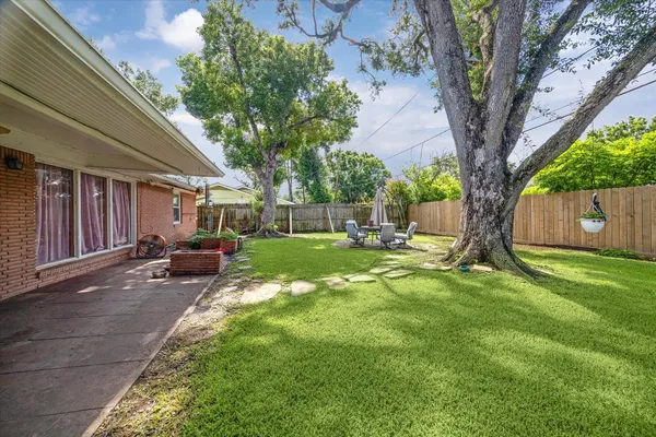 a view of backyard with a table and chairs and a large tree