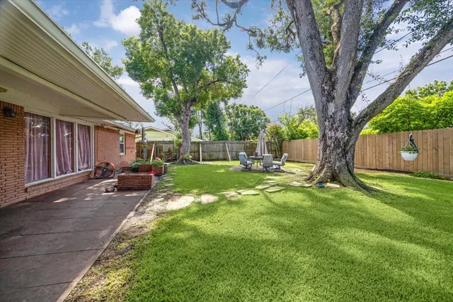 a view of backyard with a table and chairs and a large tree