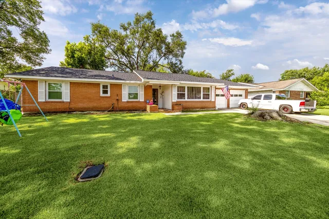 a front view of a house with a yard and trees