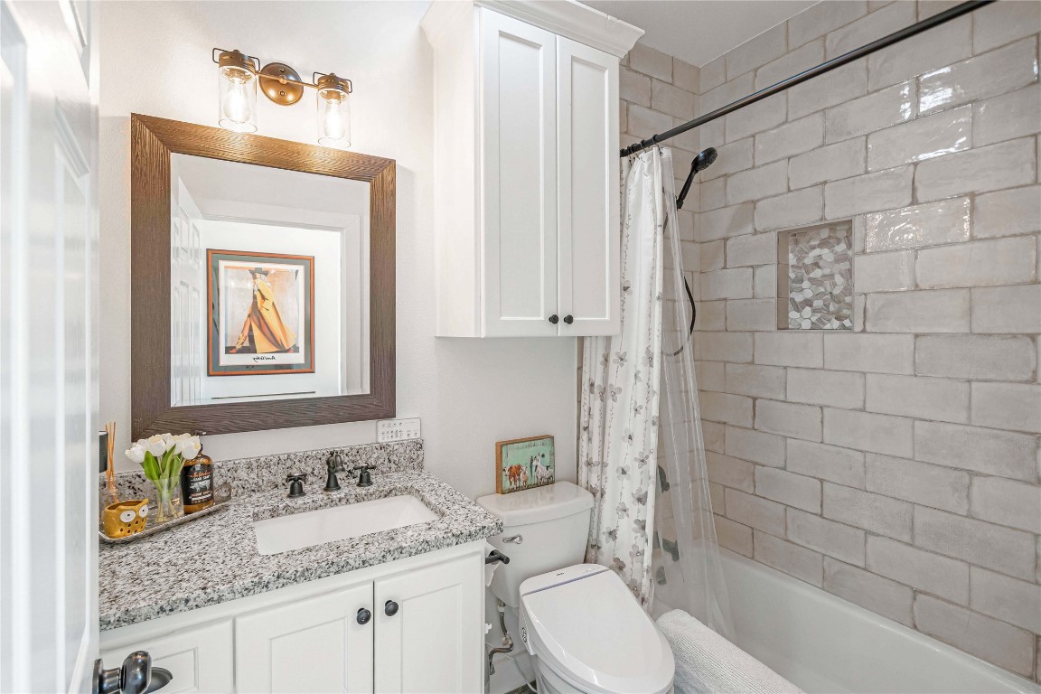 1000 Oil Field Road Lockhart, TX 78644 - Photo 24 of 39 a bathroom with a granite countertop sink a toilet and shower