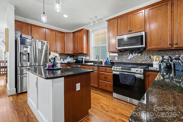 a kitchen with stainless steel appliances granite countertop a stove refrigerator and microwave
