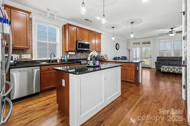 a kitchen with stainless steel appliances granite countertop a sink stove and wooden floor