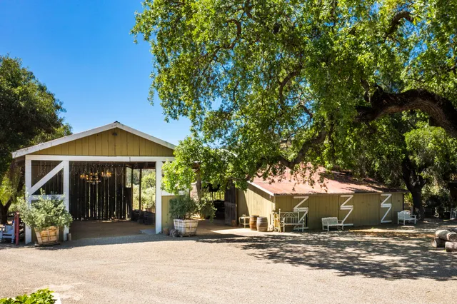 a kitchen with stainless steel appliances kitchen island a table chairs and a refrigerator