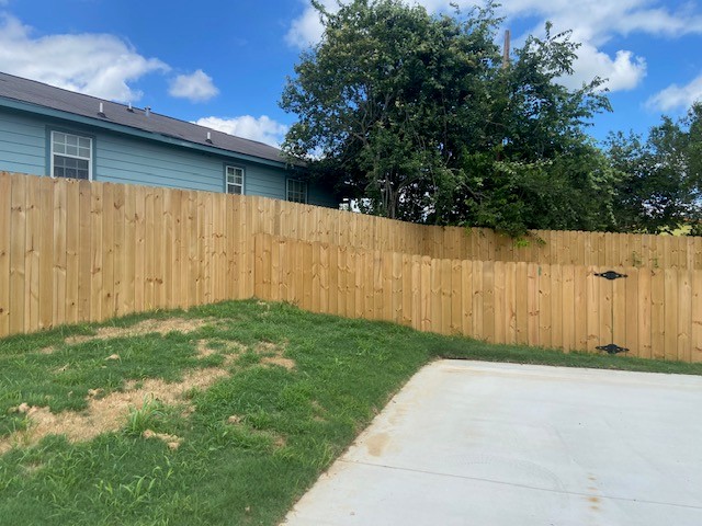 116 Field Street Luling, TX 78648 - Photo 15 of 33 A well-maintained wooden privacy fence encloses a green yard, offering seclusion for outdoor living.