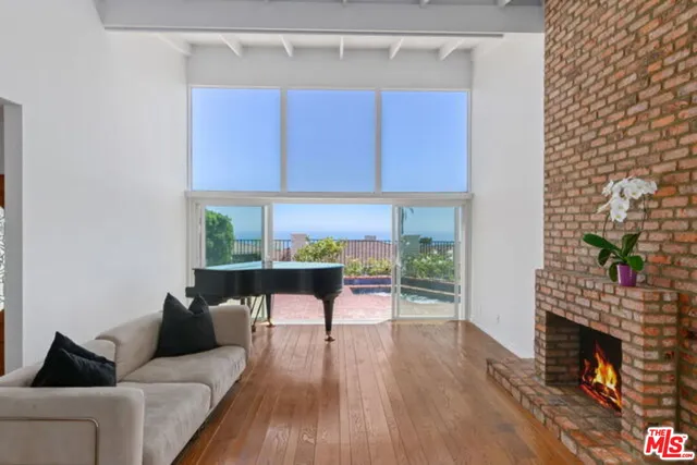 a living room with furniture a fireplace and a floor to ceiling window