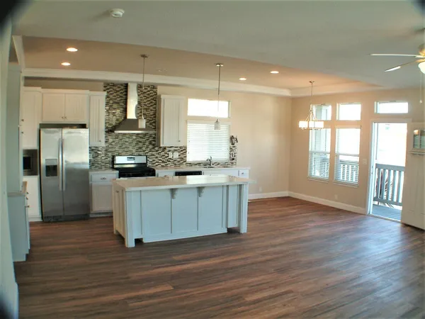 a kitchen with stainless steel appliances kitchen island wooden floors and white cabinets