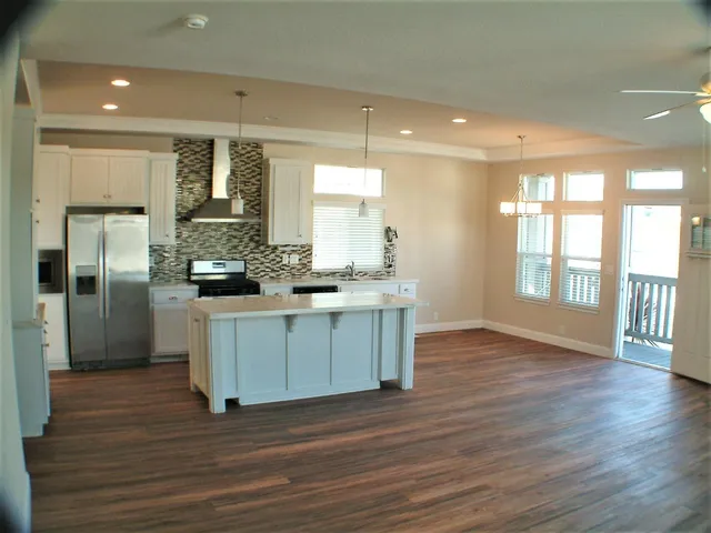 a kitchen with stainless steel appliances kitchen island wooden floors and white cabinets