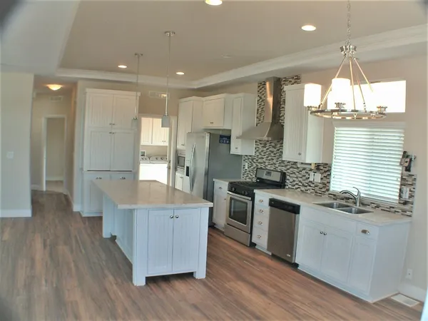 a kitchen with stainless steel appliances granite countertop a sink a stove and a refrigerator