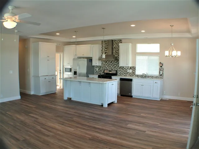 a kitchen with stainless steel appliances granite countertop a stove top oven a sink dishwasher and a refrigerator