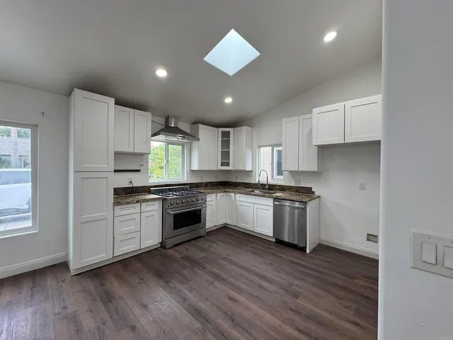 a large kitchen with a lot of cabinets and wooden floor
